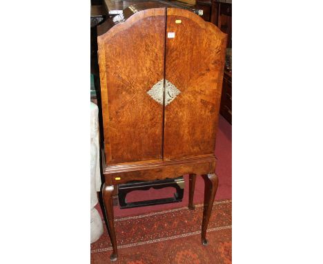 A 1930s walnut, figured walnut and crossbanded double door dome topped drinks cabinet, raised on slender elongated cabriole s