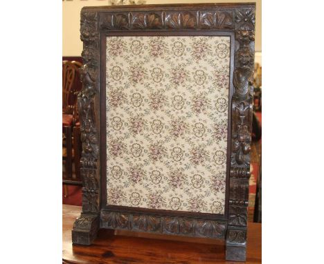 A relief carved oak fire screen having floral tapestry inset panel, 94.5 x 68cm