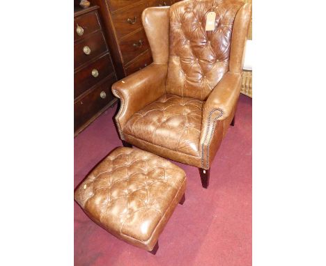 A contemporary tan leather buttoned upholstered and further studded wingback scroll armchair raised on tapering supports, wid