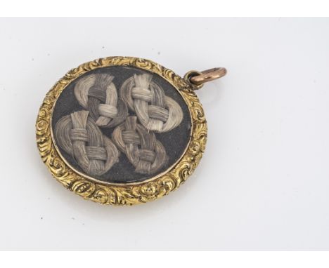 A 19th century yellow metal open hair locket,  of circular design, with engine turned back and floral scroll work engraved an
