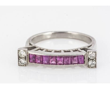 A ruby and diamond Art Deco style ring, centred with a channel set rubies, with pairs of eight cuts to each raised end, ring 