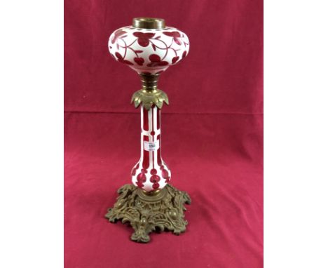A Victorian cast brass and white overlaid ruby glass oil lamp, compressed reservoir, pear shaped column, 42cm 