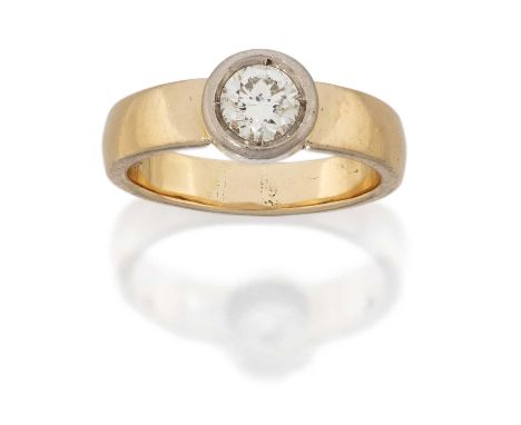 A Diamond Solitaire Ring, the round brilliant cut diamond in a white rubbed over setting, to a yellow plain polished shank, e