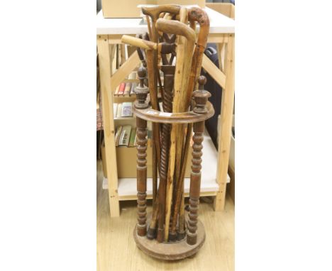   A circular turned beech stick stand, containing various walking sticks and a shooting stick