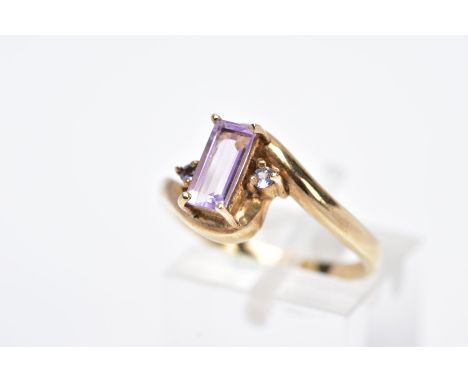 A 9CT GOLD AMETHYST RING, designed with a claw set rectangular cut amethyst flanked with circular cut purple stones assessed 