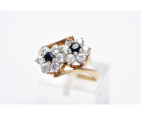 A 9CT GOLD SAPPHIRE AND CUBIC ZIRCONIA DOUBLE CLUSTER RING, designed with two asymmetrical clusters, each set with a central 