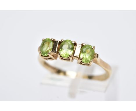 A 9CT GOLD THREE STONE PERIDOT RING, designed with three claw set, oval cut peridots, hallmarked 9ct gold Birmingham, ring si