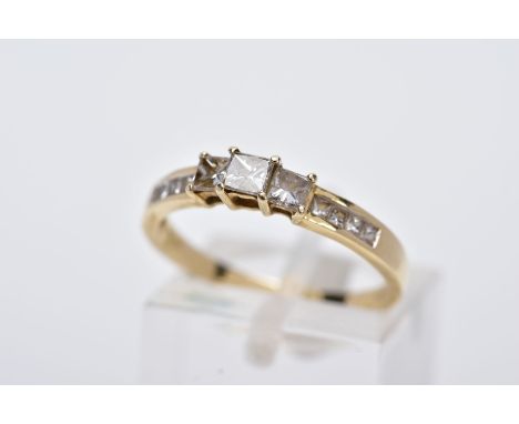 A 14CT GOLD DIAMOND RING, designed as a half eternity ring set with three raised princess cut diamonds flanked with princess 