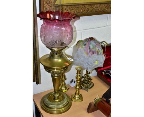 A BRASS OIL LAMP, with clear funnel and ruby coloured wavy edged glass shade, total height to top of shade 55cm, together wit