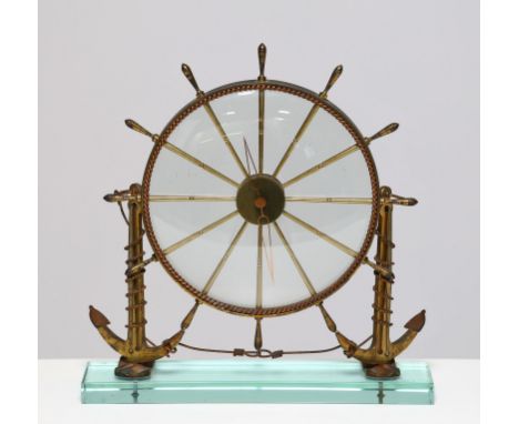 Table clock. Brass and glass. Cm 38,00 x 40,00 x 9,00. Glass structure with brass details depicting anchor and rudder; 40s.