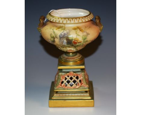 A Royal Worcester two handled ogee shaped pedestal vase, printed and painted with thistles on a blush ivory ground, the stand
