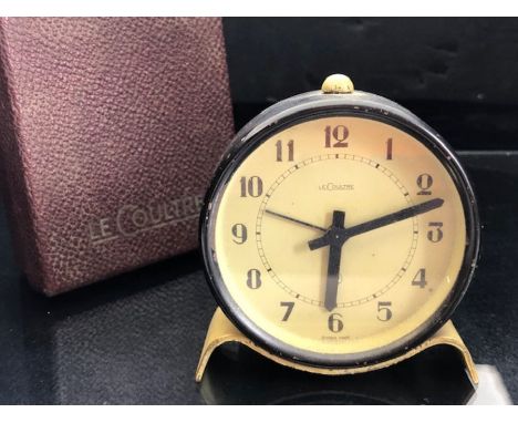 Vintage Le Coultre alarm clock, in a black circular case on a cream shaped stand, in original box