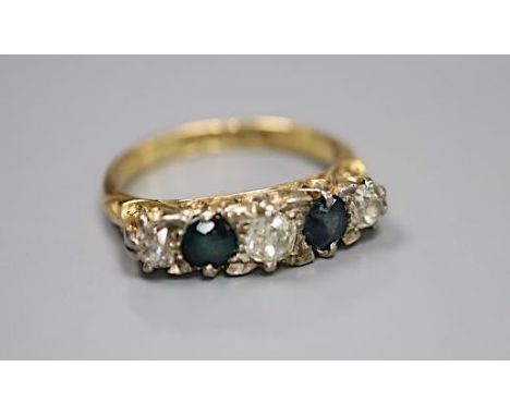 An early 20th century 18ct gold three stone diamond and two stone sapphire set half hoop ring, size K, gross 3.6 grams.