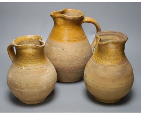 A group of three late 19th century part glazed Verwood pottery pitchers, tallest 25cm