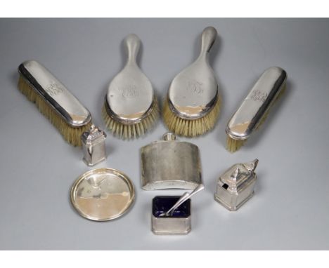 A George V engine turned silver hip flask, four silver mounted brushes, three piece condiment set and two small dishes.