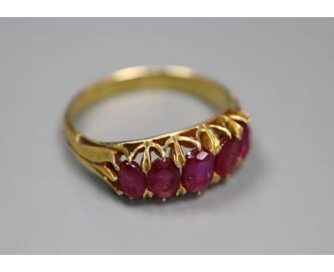 A yellow metal and graduated five stone ruby set half hoop ring, three stone a.f., size M, gross 3.4 grams.