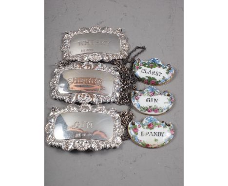 A pair of silver decanter labels, 0.9oz troy approx, a silver plated on copper decanter label and three ceramic decanter labe