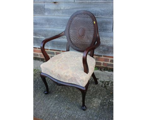An early 20th century mahogany showframe elbow chair with cane back panel and a mahogany dressing stool with dished seat, on 