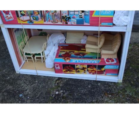 A Sindy three-storey doll's house, two Sindy dolls, a selection of Sindy doll's furniture comprising a Sindy "Studio", "Barbe