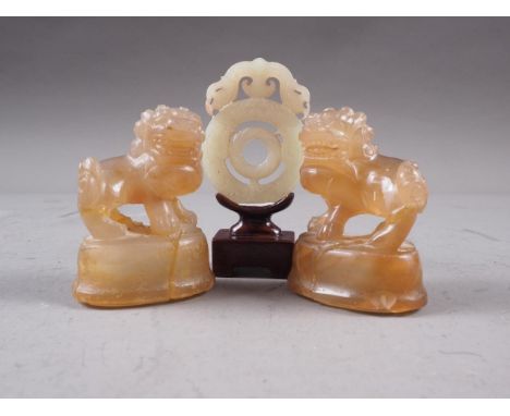 A Chinese green jade roundel with carved and pierced decoration, on stand, 2 3/4" high overall, and a pair of carved agate Do