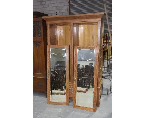 A late Victorian satinwood wardrobeHaving an over hanging pediment above a pair of mirrored doors and a single drawer applied