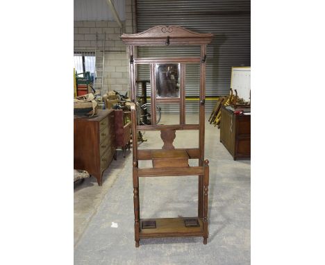 An early 20th Century oak hall stand Having a rail back centred with a rectangular bevelled mirrored plate above a hinged glo