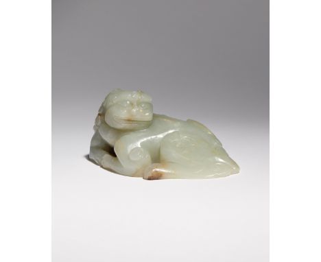 A CHINESE CELADON JADE CARVING OF A LION DOG MING/QING DYNASTY Depicted in a recumbent pose turning its head to sinister, the