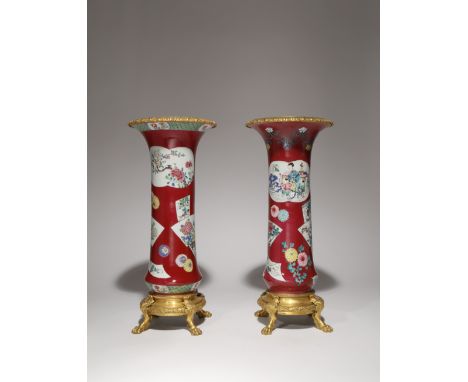 A NEAR PAIR OF CHINESE FAMILLE ROSE RUBY-GROUND ORMOLU-MOUNTED BEAKER VASES THE PORCELAIN 18TH CENTURY, THE MOUNTS 19TH CENTU