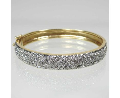 A 14 carat gold and diamond set graduated bangle, of hinged design, with safety catch, pave set with one hundred and thirty t