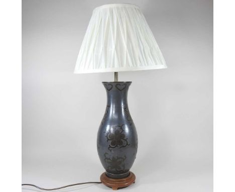 A metal table lamp, with relief decoration and a cream shade, 76cm high overall
