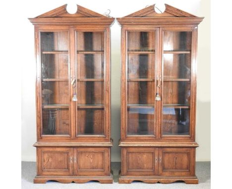 A pair of modern glazed oak bookcases, fitted with glazed shelves, each with a broken arch cornice and cupboards below101w x 