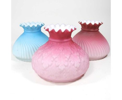 Two pink oil lamp shades, together with another, blue, each with a frilled rim and 13cm aperture (3)All are dirty, with light