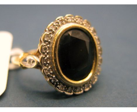 A Sapphire and Diamond Oval Cluster Ring, collet rubover set to the centre, within border of single cut diamonds, between ins