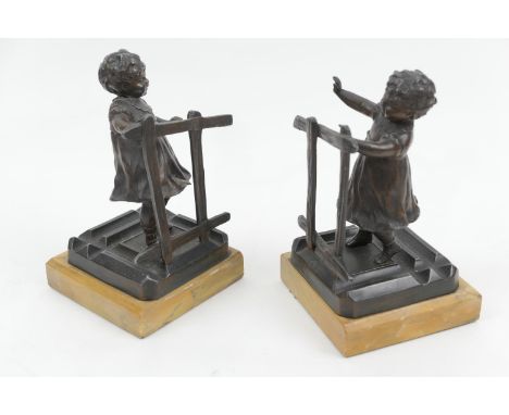 Pair of late Victorian bronzed spelter bookends, circa 1900, cast as children playing blind man's buff, mounted on yellow mar