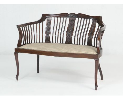 Late Victorian mahogany window seat, circa 1900, the curved stick back with three carved foliate splats, cream fabric pad sea