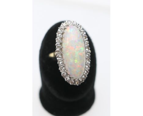 Opal and diamond cluster ring, centred with a cabochon opal, 25mm x 10mm, depth approx. 13mm, in an 18ct white gold claw moun