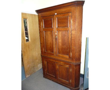 A Georgian Oak four door floor standing Corner Cupboard with panelled doors, brass hinges and escuthcheons, 53'' wide x 78 1/