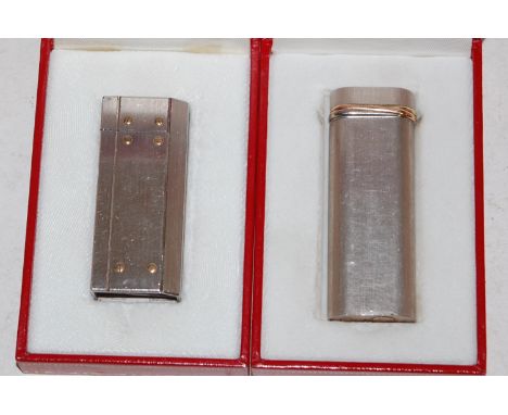A Must de Cartier pocket cigarette lighter in fitted red leather box with paperwork together with one other similar example (