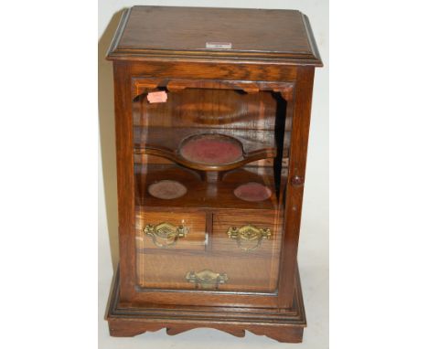 An Edwardian oak smoker's cabinet having fitted interior enclosed by a glazed door on a plinth base, height 44cm