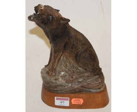 A modern resin figure in the form of a seated wolf on a wooden plinth