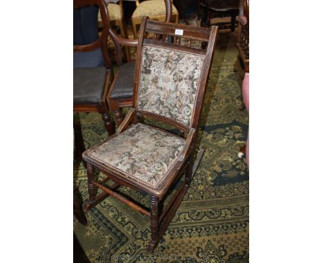 An arts and crafts stained Beech framed Rocking Chair, reeded back frame with spindle detail and padded section and padded se