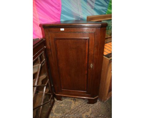 A late 19th c. Oak floor standing Corner Cabinet, having moulded edge later top, single panel, cross banded long door, on low