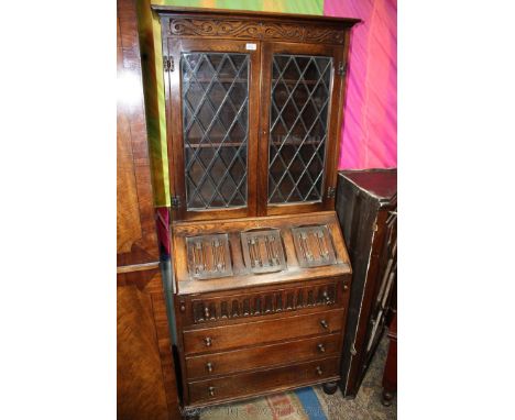 A good reproduction Oak Priory style Bureau Bookcase, having moulded cornice over carved frieze, over a pair of opposing lead