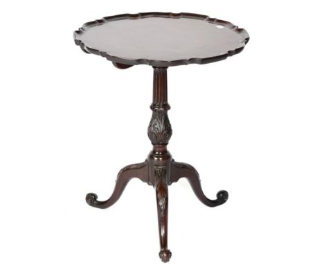 A George III Mahogany Fliptop Tripod Table with associated moulded pie crust top above a fluted and acanthus carved baluster 