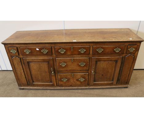 A George III Oak Enclosed Dresser, late 18th century, with an arrangement of five frieze drawers and two deep drawers below f