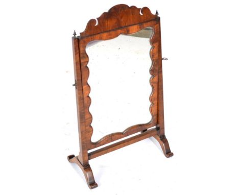 A Walnut Dressing Table Mirror, the mercury plate contained within a moulded frame with shaped pediment, raised on a frame wi