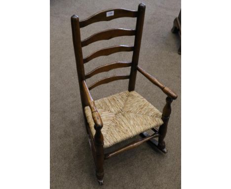 A 19th Century Child's Ash and Rush Seated Ladder-Back Rocking Armchair, with spindle arm supports, the legs joined by an H s