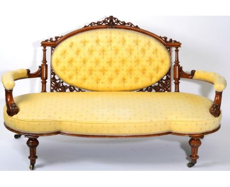 A Victorian Walnut Framed Sofa, circa 1870, recovered in yellow button-back fabric with an oval overstuffed back support, wit