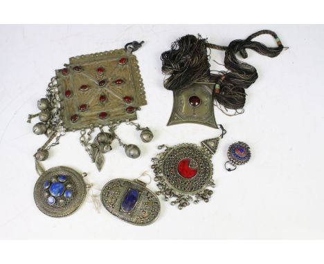 Collection of middle eastern silver white metal pendants to include an Afghan coloured gem set pendant, two wire work detaile