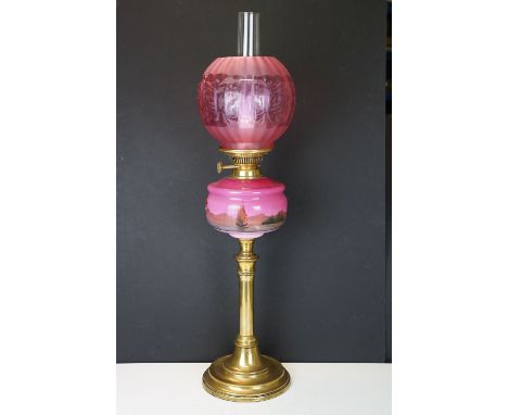 Late Victorian / early 20th Century oil lamp having a round brass stepped base, pink reservoir with hand painted landscape sc